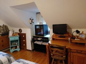 隆格伊Refuge du Poète的一间卧室配有一张桌子、一台电脑和一台电视机
