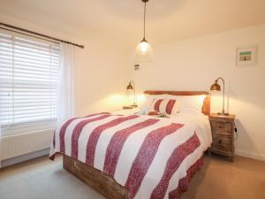绍斯沃尔德4 East Green, Southwold的一间卧室配有带条纹棉被的床和窗户