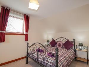 洛哈尔什教区凯尔高地25 Langlands Terrace的一间卧室配有一张带紫色枕头的床和窗户。