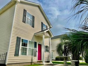 默特尔比奇Lovely Home Near Myrtle Beach的一间白色的房子,有红色的门和棕榈树