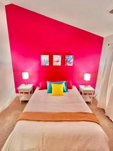 默特尔比奇Lovely Home Near Myrtle Beach的粉红色的卧室,配有一张大床和两张桌子