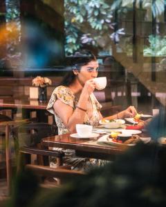 特纳Arahuana Jungle Resort & Spa的坐在桌子上喝咖啡的女人