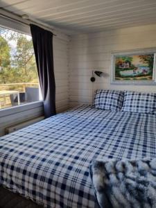 TyresöNils Bastu Spa och Övernattningstuga的卧室配有蓝色和白色的格子床和窗户