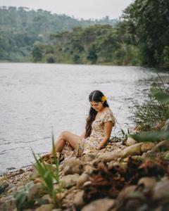 特纳Arahuana Jungle Resort & Spa的坐在岩石上的水边的女人