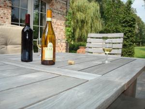 赫尔B&B Hooglandhoeve的一瓶葡萄酒和一张木桌上的玻璃杯