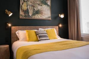 多维尔Hotel Le Patio - Deauville的一间卧室配有黄色和白色枕头的床