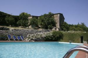 基安蒂盖奥勒Badia a Coltibuono Wine Resort & Spa的一个带两把椅子和石墙的游泳池