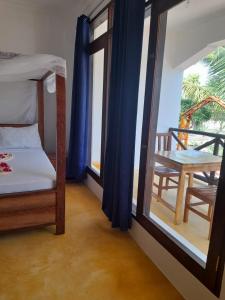 南威Majani Breeze的一间卧室配有一张床、一张桌子和一个窗户。