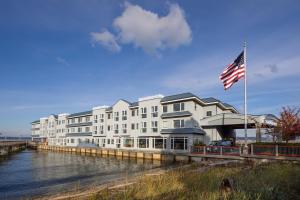 塔科马Silver Cloud Hotel Tacoma Waterfront的一座大型白色建筑,水边挂着美国国旗