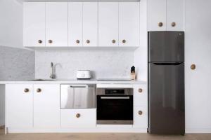 悉尼Studio Bondi Beach的厨房配有白色橱柜和黑色冰箱。