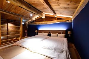 白马村Hakuba Hatago Maruhachi的一间卧室配有一张白色大床和蓝色的墙壁
