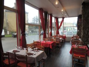 阿朗松哈萨德酒店的一间带桌椅和红色窗帘的餐厅