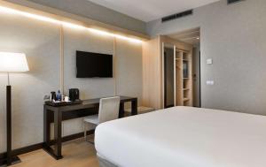 马德里NH马德里里贝拉格兰德曼萨纳雷斯酒店的酒店客房配有一张床和一张书桌及一台电视