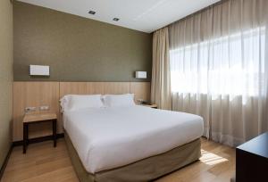马德里NH马德里里贝拉格兰德曼萨纳雷斯酒店的卧室设有一张白色大床和一扇窗户。