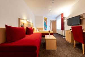 涅德托辛根Gasthaus Hotel Zum Mohren的酒店客房配有红色的沙发和床。