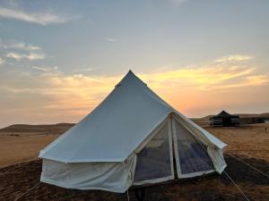 ShāhiqDesert Private Camps -ShootingStar Camp的沙漠中的帐篷,背景是日落