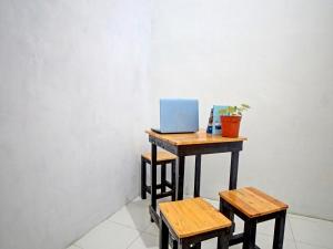 SunggalOYO 91959 La Khansa Homestay Syariah的一张桌子,上面有一台笔记本电脑和两张凳子