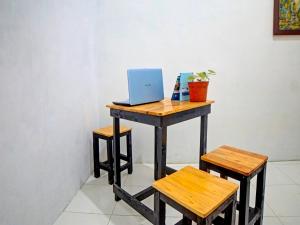 SunggalOYO 91959 La Khansa Homestay Syariah的一张桌子,上面有一台笔记本电脑和两张凳子