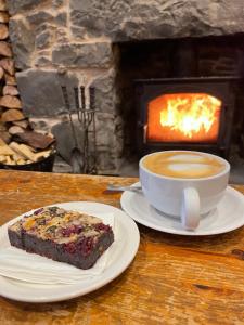 凯里肯Glenarroch & Witchwood的一块蛋糕和一杯咖啡,放在带壁炉的桌子上
