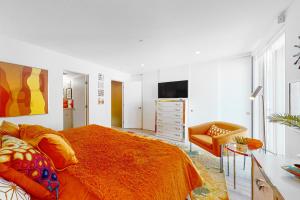 棕榈泉Upscale Uptown Permit# 5251的一间卧室配有一张带橙色毯子和椅子的床