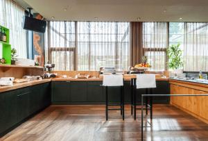 斯德勒基Tailormade Hotel SIHLPARK Schindellegi的厨房配有深绿色的橱柜和白色的凳子