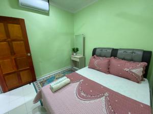 马日丹那Green Home Homestay Melaka的一间卧室配有一张带粉红色枕头和镜子的床