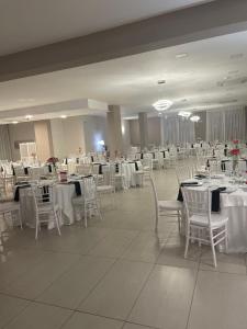 BruscianoHotel Villa Ruggiero的宴会厅配有白色的桌子和白色的椅子