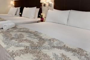 伦敦贝斯特韦斯特伦敦奇司威克宫套房酒店的配有白色床单的酒店客房内的两张床