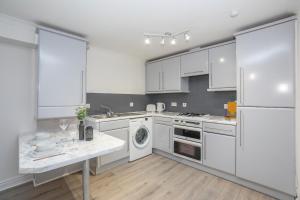 阿伯丁Panacotta House - Luxury 1 Bed Apartment in Aberdeen的厨房配有白色橱柜、洗衣机和烘干机