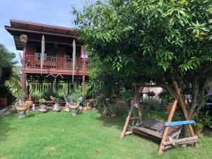 Ban Kho SaiMetha Country View Homestay Singburi的一个带树和秋千的房子的院子