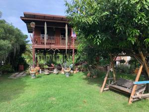 Ban Kho SaiMetha Country View Homestay Singburi的一座带甲板和植物庭院的房子