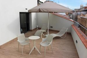 马德里Apartamentos Centro Jardines的阳台配有四把椅子和一张桌子,阳台配有雨伞