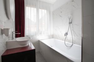 维也纳ARTIST Boutique Hotel的白色的浴室设有浴缸和水槽。