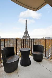 巴黎CMG Tour Eiffel/ New York的阳台配有三把椅子和一张桌子,阳台设有艾菲尔铁塔