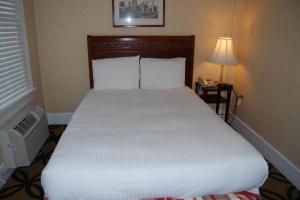 华盛顿Windsor Inn Hotel的卧室配有白色床、灯和电话