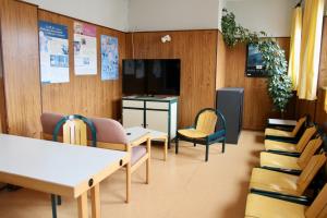 科尔马AUBERGE DE JEUNESSE的一间设有桌椅和电视的等候室