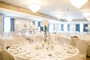GeesalaErris Coast Hotel的宴会厅配有白色的桌子和白色的椅子