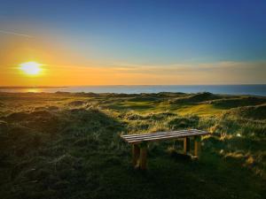 GeesalaErris Coast Hotel的坐在田野顶上边的长凳,享有日落美景