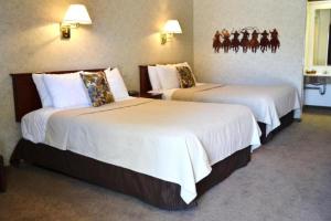LuskCovered Wagon Motel Lusk WY的酒店客房,配有两张带白色床单的床