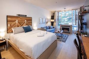 惠斯勒Bright Suite at Ski In/Out Glacier Lodge!的一间卧室设有一张大床和一个壁炉