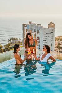 利马Iberostar Selection Miraflores的一群三个女人坐在游泳池里