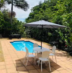 德班Modern Luxury 3 bedroom house的游泳池旁配有遮阳伞的桌椅