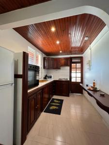 勒拉芒坦Poseidon的厨房配有木制橱柜和白色冰箱。
