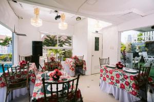 BalangaGrand Peninsula Suites的用餐室配有2张桌子和椅子,并装饰有红色的鲜花