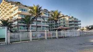 里约热内卢Meu Resort no Recreio - RJ的棕榈树建筑前的白色围栏