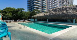 圣玛尔塔Hotel Los Veleros Santa Marta的一个带椅子和茅草屋顶的游泳池