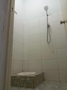 龙目岛库塔Sulis homestay的白色瓷砖浴室设有淋浴和卫生间