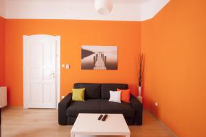 布达佩斯City Centre Apartment with 3 Bathrooms的客厅配有黑色沙发和橙色墙壁