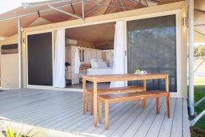 哈灵顿Crowdy Bay Eco Resort的木甲板配有桌子和床