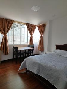 洛哈Habitaciones Alkimya的一间卧室配有一张床、一张桌子和一个窗户。